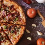 Durch Pizzaschere geschnittene Pizza mit Tomaten und Knoblauch